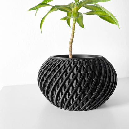 Pot décoratif noir mat en plastique avec motif torsadé en spirale, forme ronde et large, contenant une plante verte.