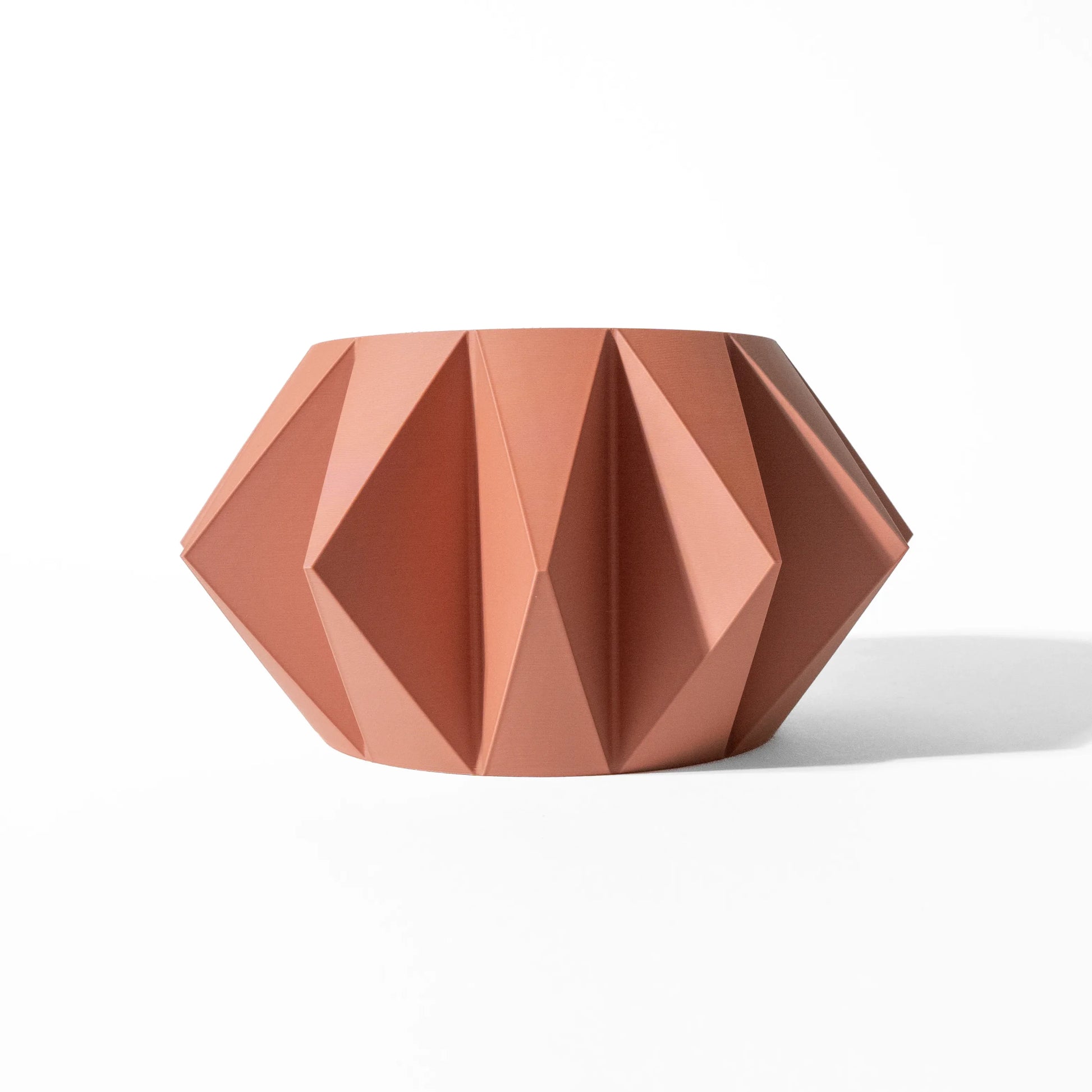 Pot décoratif terracotta en forme géométrique facettée, style moderne minimaliste.