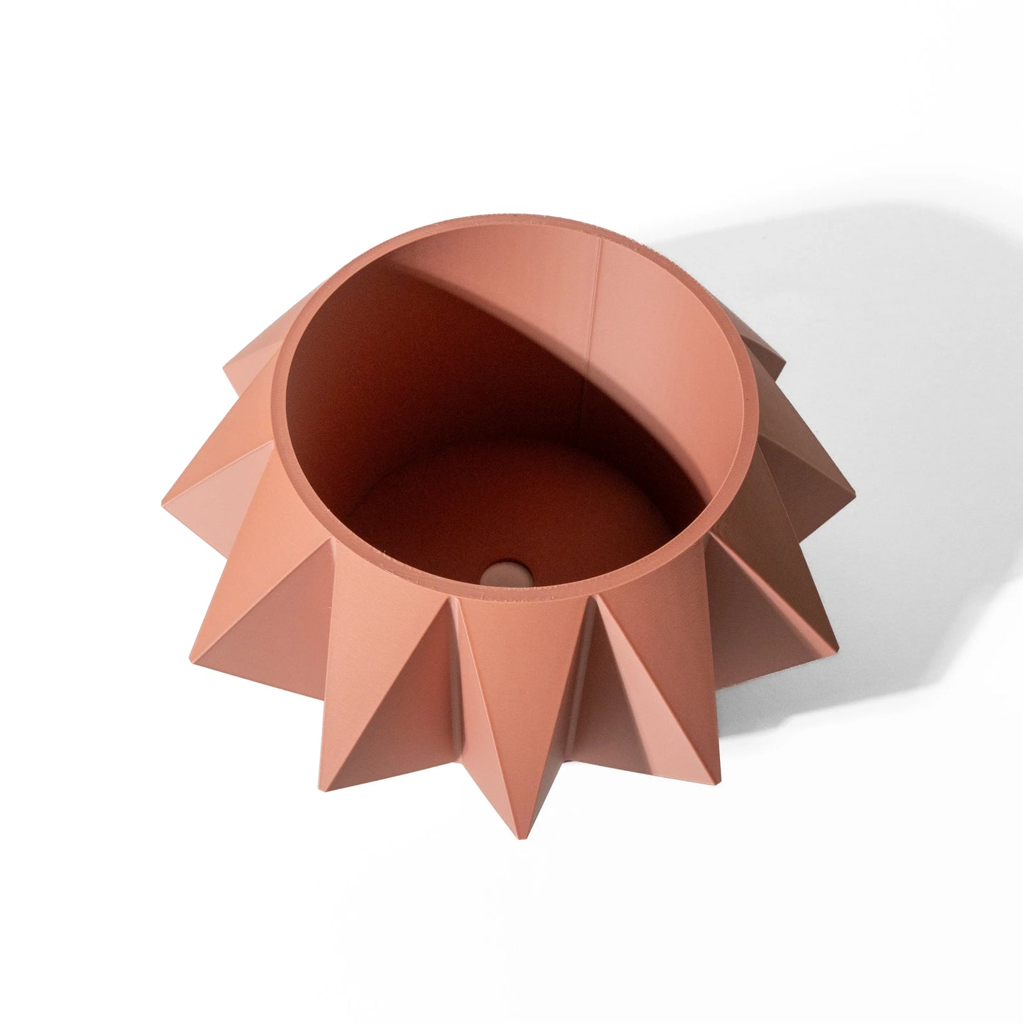 Pot décoratif terracotta en forme conique avec facettes géométriques et bord rond lisse, style moderne.