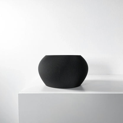 Pot décoratif noir mat, forme ronde bombée avec surface texturée rayée verticale, style moderne.