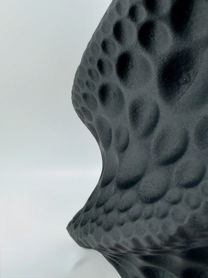 Vase sculptural noir mat en matériau durable, surface texturée avec motifs torsadés, design contemporain et étanche.