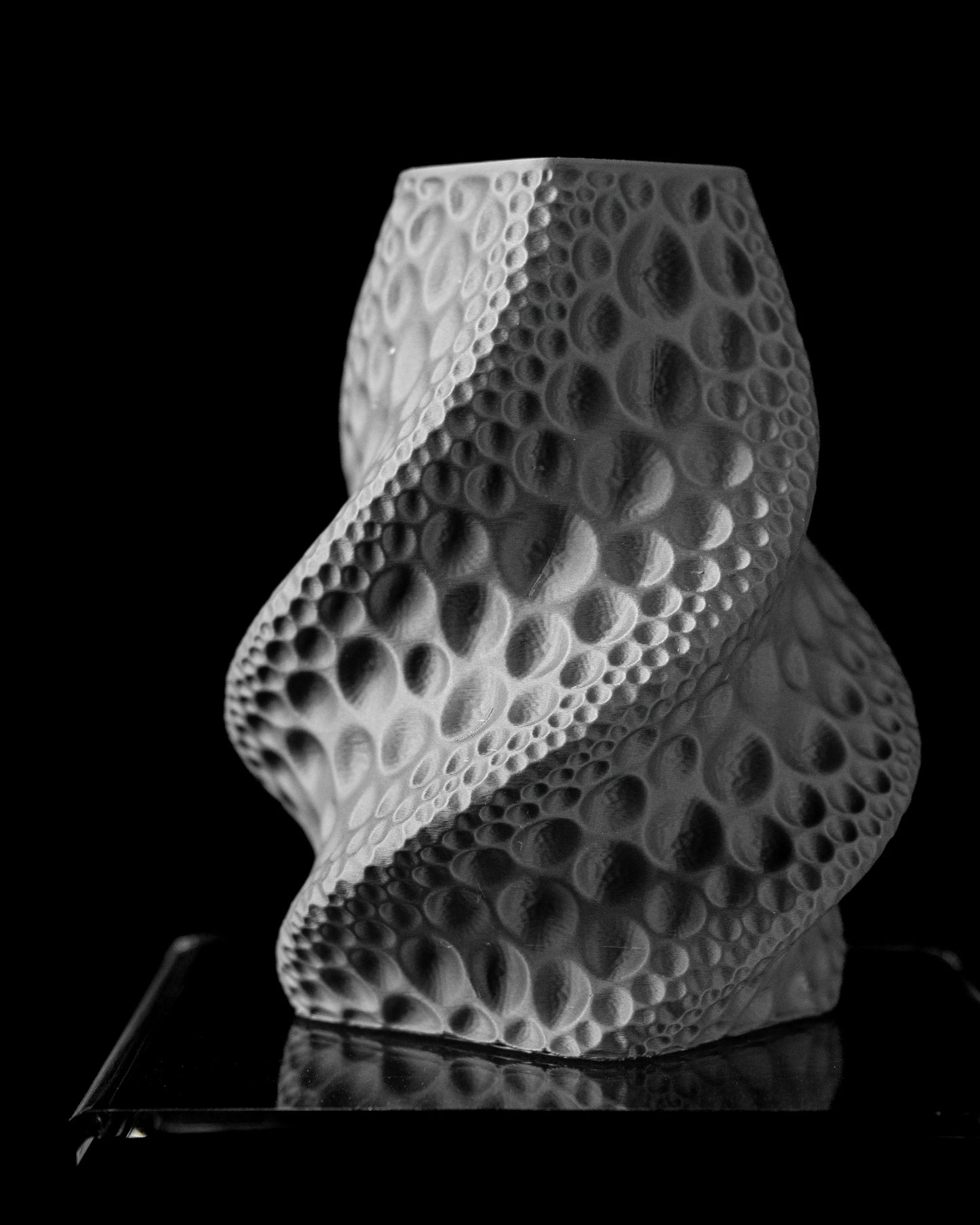 Vase blanc mat en spirale texturé de motifs creux ovales rappelant la surface lunaire, forme moderne et sculpturale.
