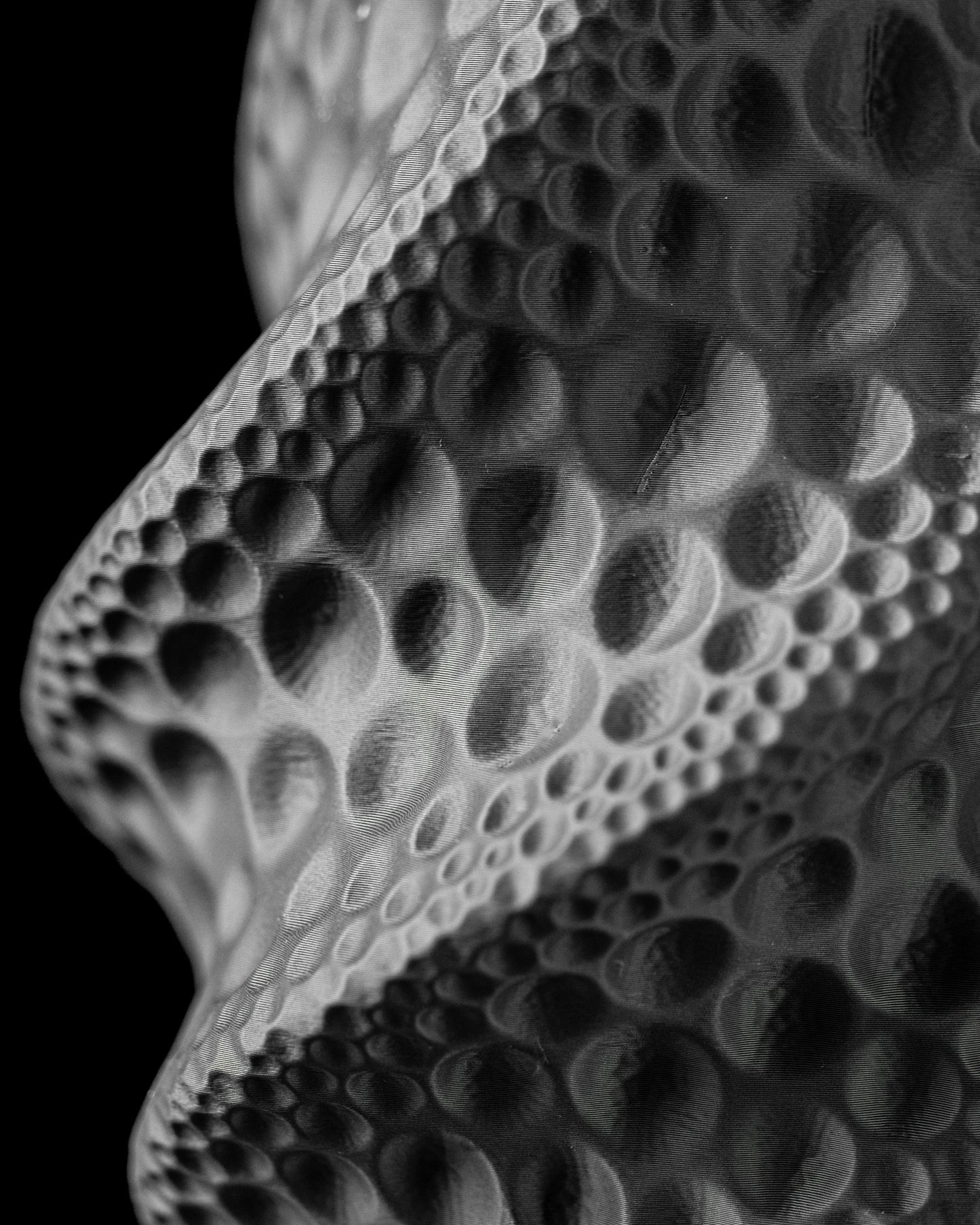 Vase noir à surface ondulée avec motifs texturés en relief évoquant des bulles de tailles variées.