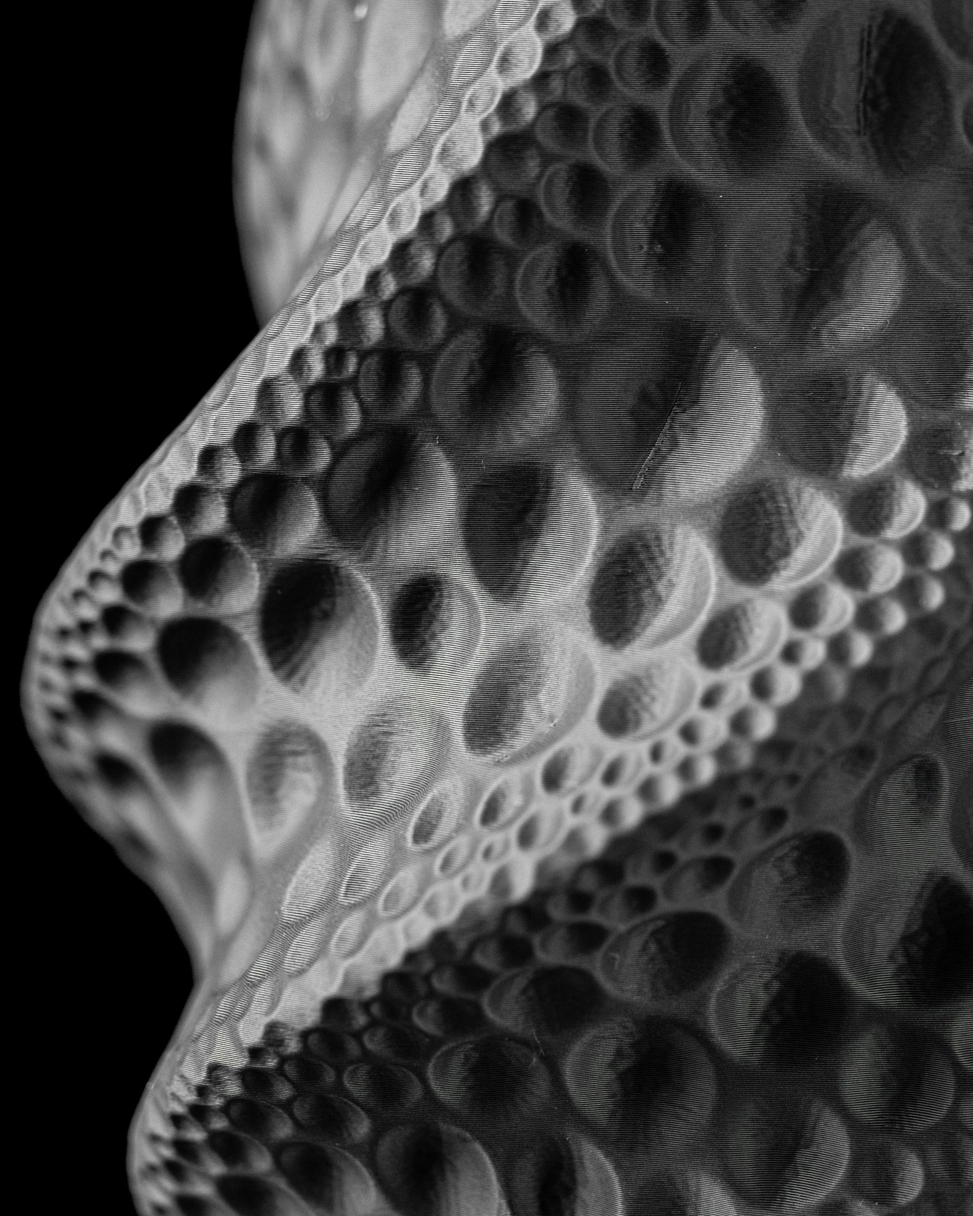 Vase noir à surface ondulée avec motifs texturés en relief évoquant des bulles de tailles variées.