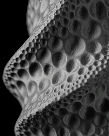 Vase noir à surface ondulée avec motifs texturés en relief évoquant des bulles de tailles variées.