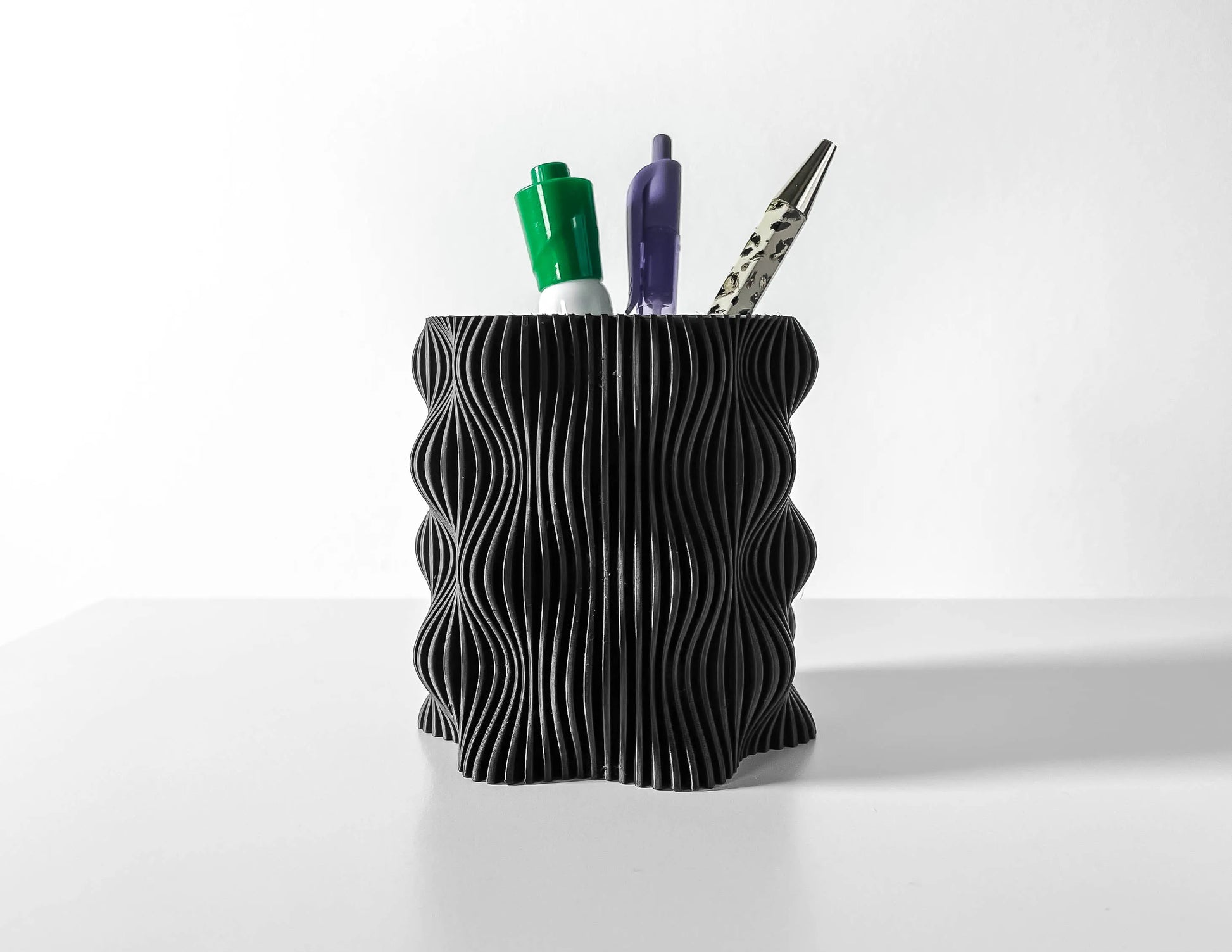 Pot décoratif anthracite en plastique durable avec design contemporain à surface ondulée, utilisé comme porte-stylos.
