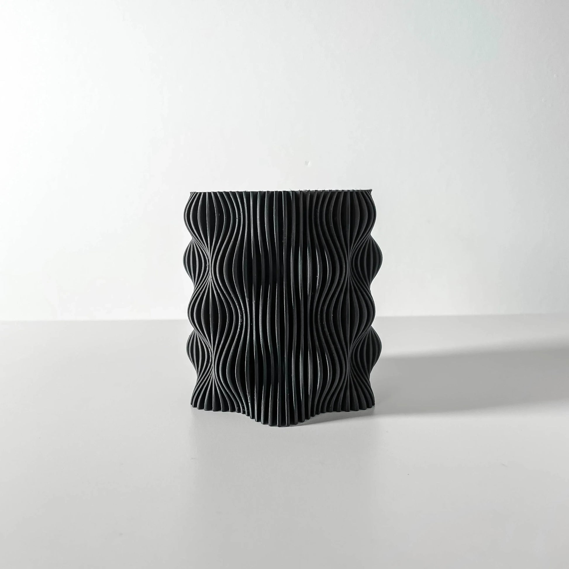 Pot décoratif anthracite en matériau durable avec design contemporain ondulé et texturé.