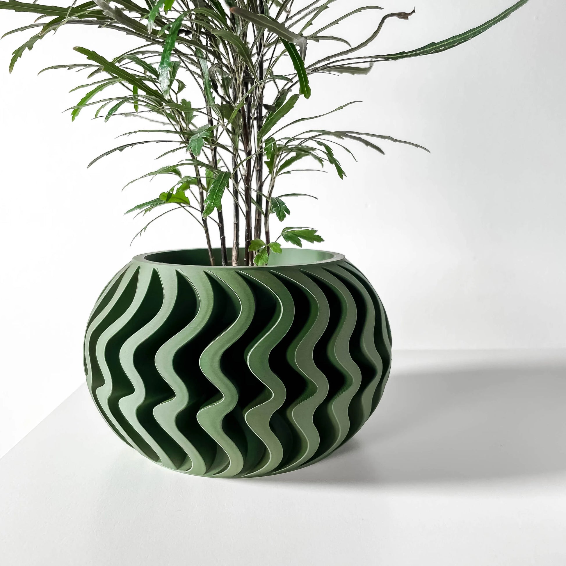 Pot décoratif vert forêt à ondulations en relief, forme ronde avec design contemporain durable.