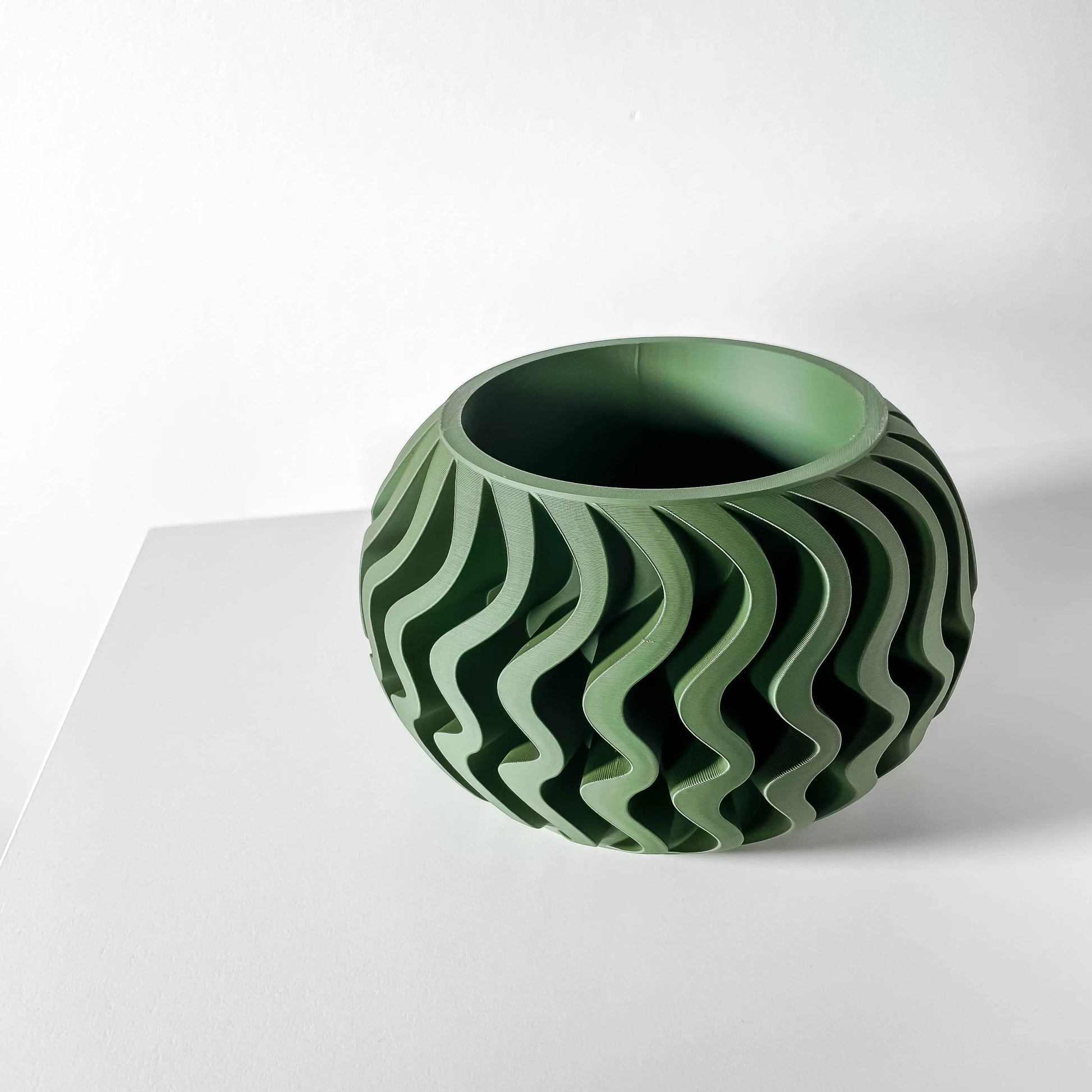 Pot décoratif Noli vert forêt au design contemporain, surface texturée ondulée, matériau durable et moderne.