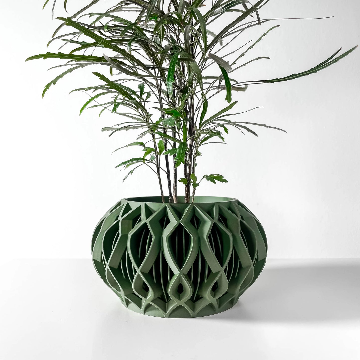 Pot décoratif vert forêt en matériau durable à design contemporain ajouré et géométrique.