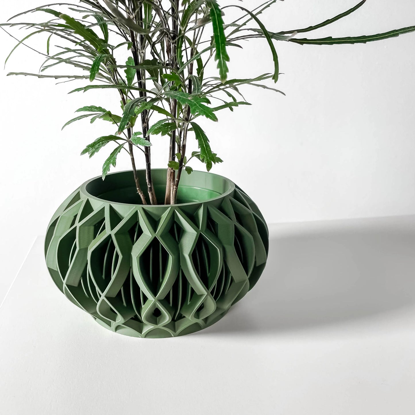 Pot décoratif contemporain vert forêt en matériau durable avec design géométrique ajouré circulaire.