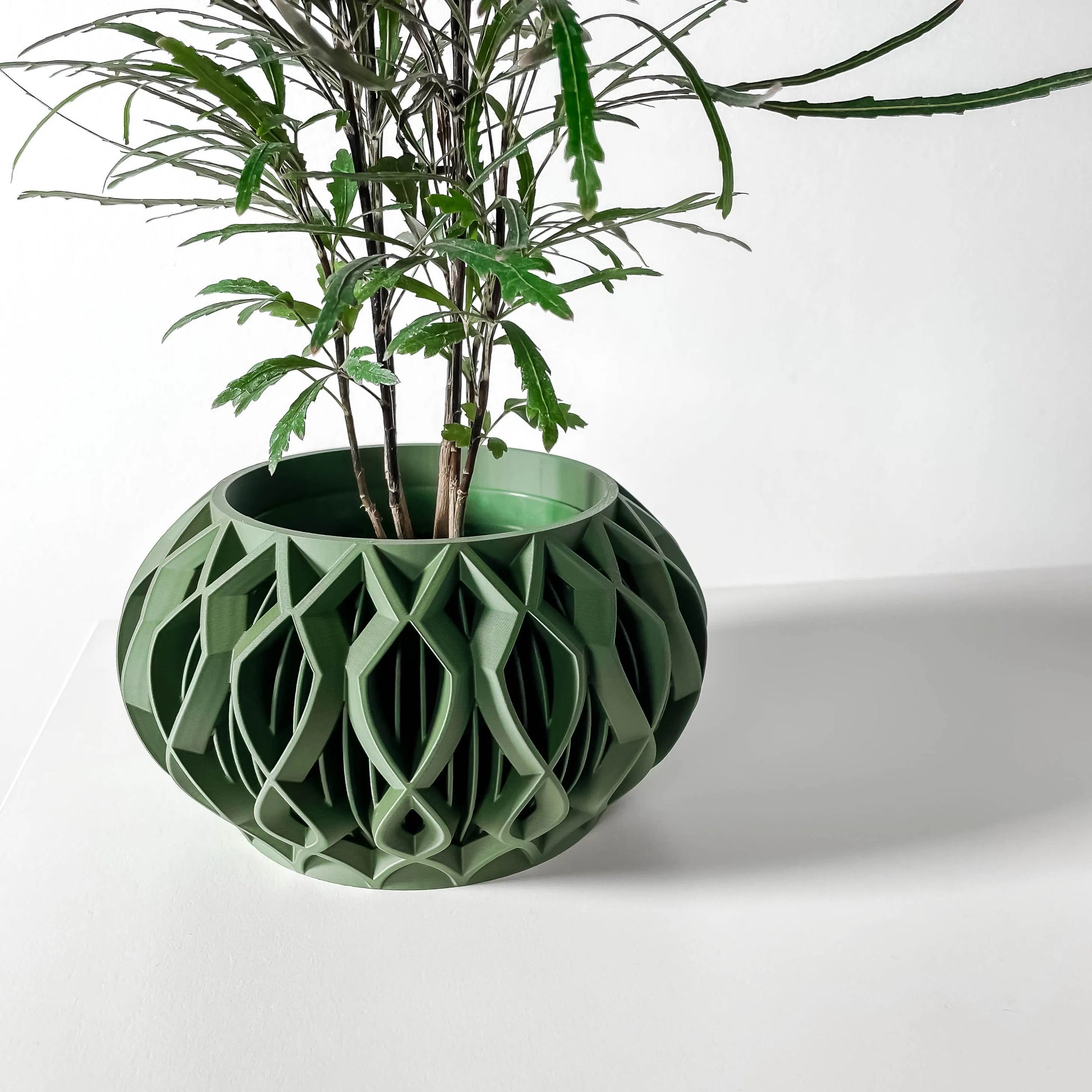 Pot décoratif contemporain vert forêt en matériau durable avec design géométrique ajouré circulaire.