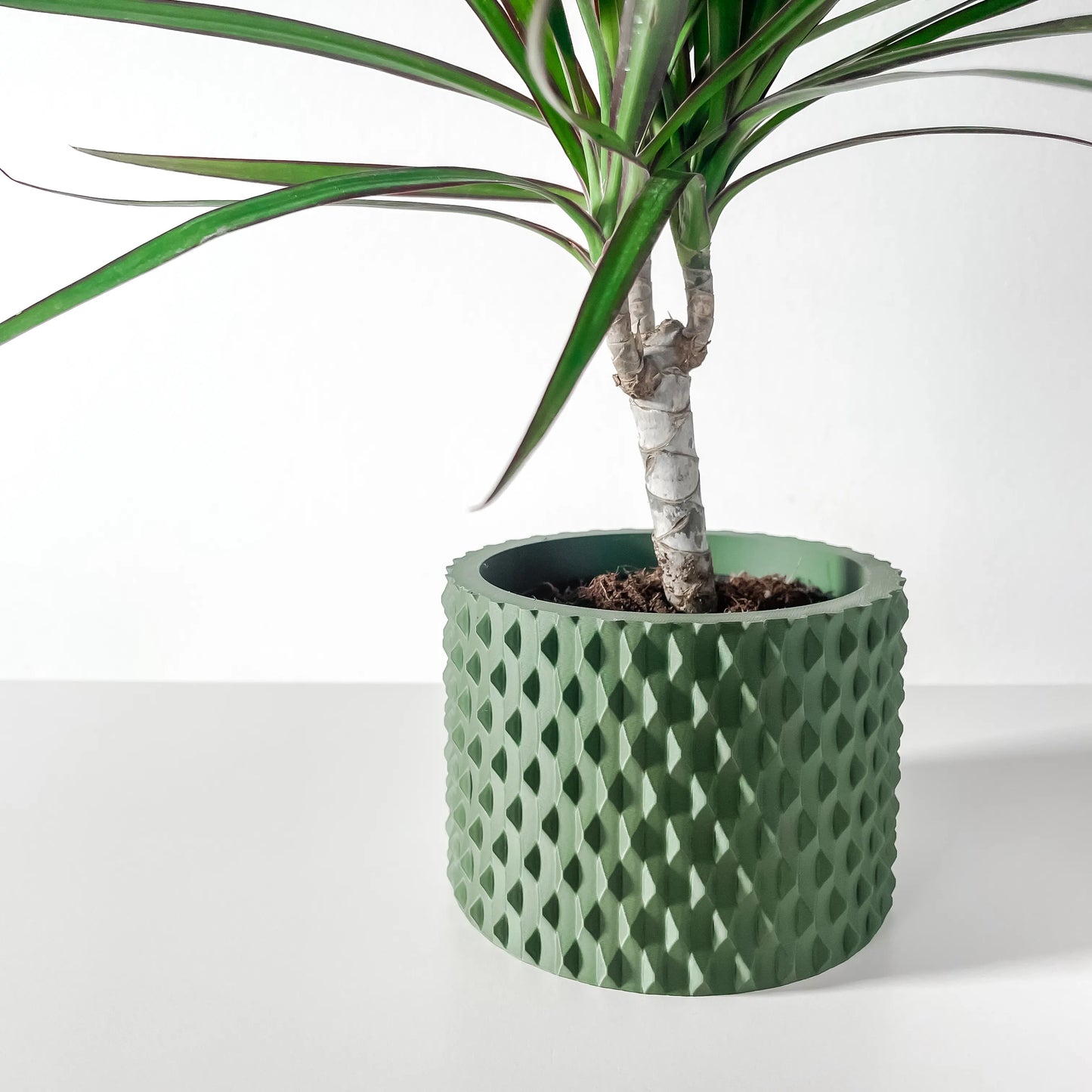 Pot décoratif vert forêt en matériau durable, design contemporain avec surface texturée ondulée, plante verte insérée.