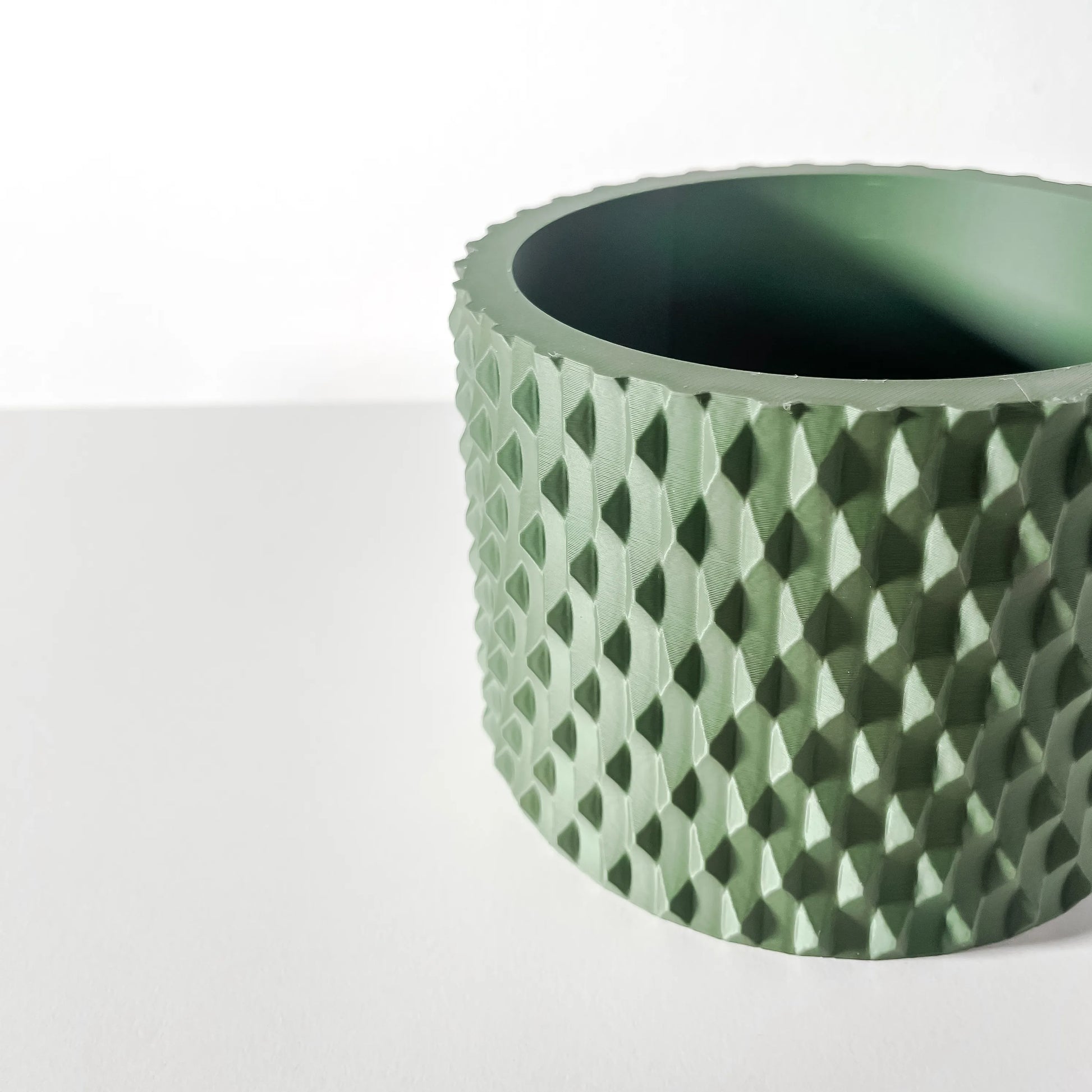 Pot décoratif Ondir vert forêt en matériau durable avec surface texturée à motifs géométriques, design contemporain.