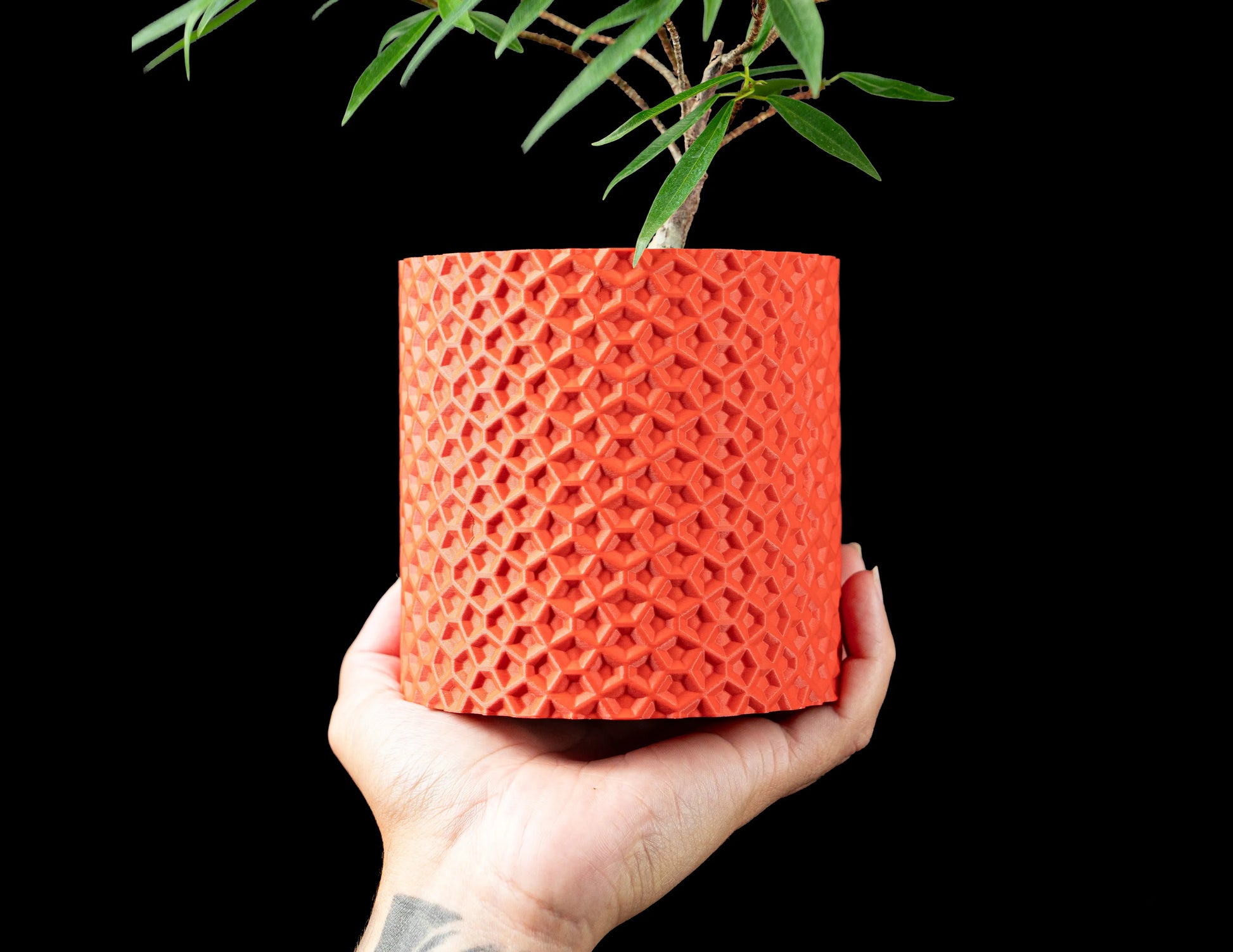 Pot décoratif Ordan orange en matériau durable avec surface texturée en motif géométrique contemporain, tenue à la main.