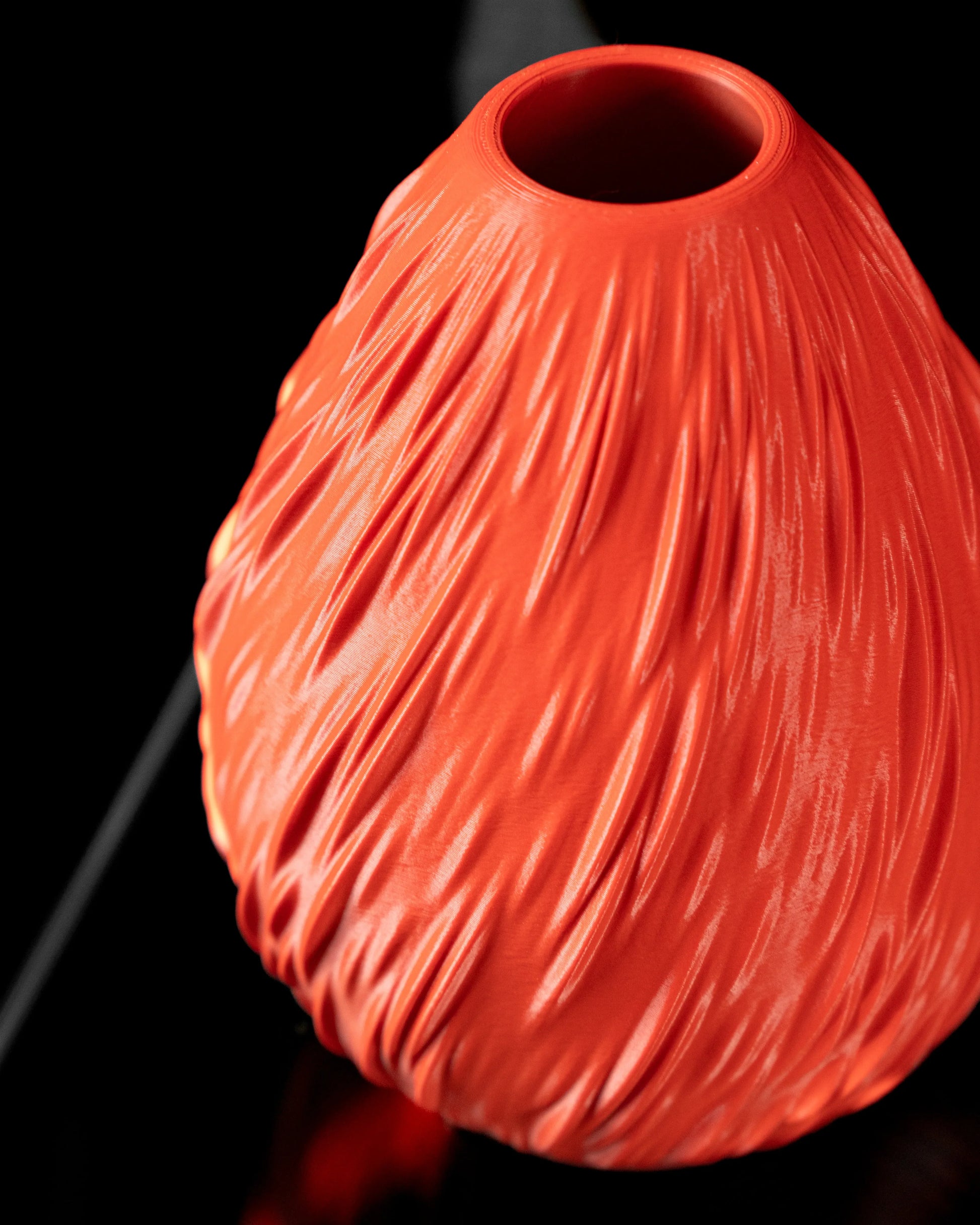 Vase orange vif avec texture ondulée rappelant des gouttes de pluie, surface mate, forme ovoïde, ouverture ronde en haut.