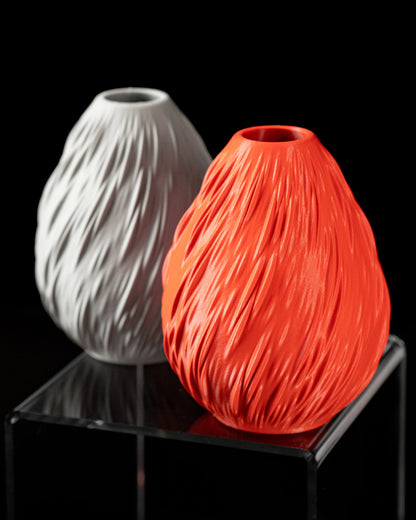 Deux vases étanches modernes en plastique, forme ovale avec motifs ondulés, un rouge vif et un blanc mat, posés sur un.