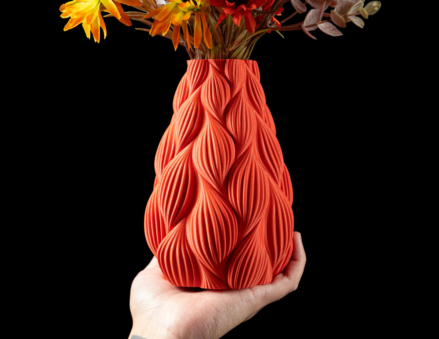 Vase rouge contemporain en matériau durable avec design ondulé texturé, tenue à la main.