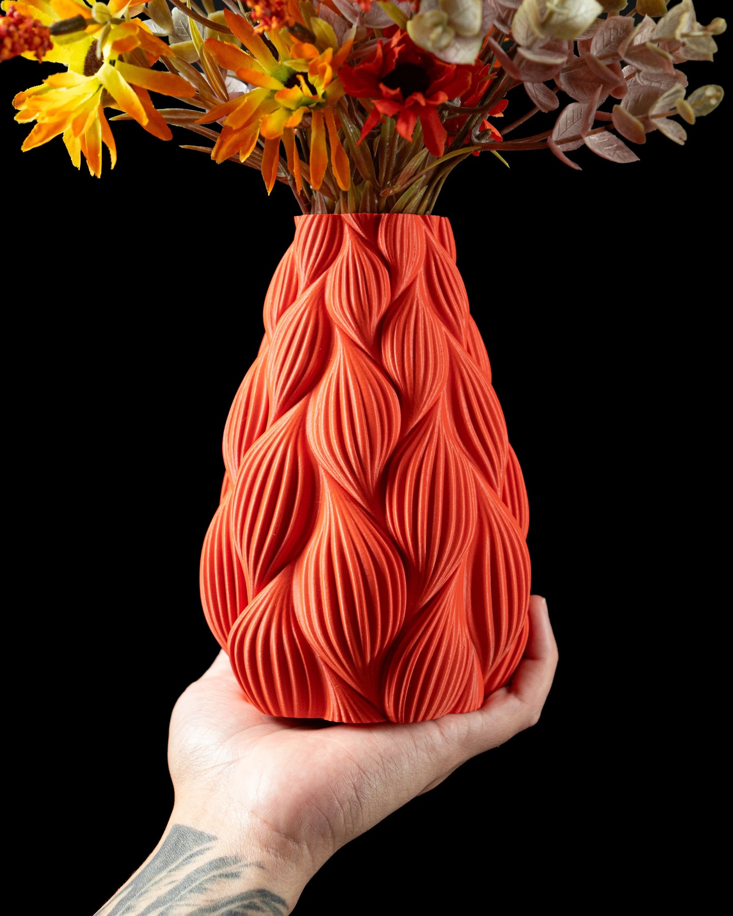 Vase contemporain rouge orangé effet nervuré ondulé, design durable en matériau moderne, étanche, tenu à la main.