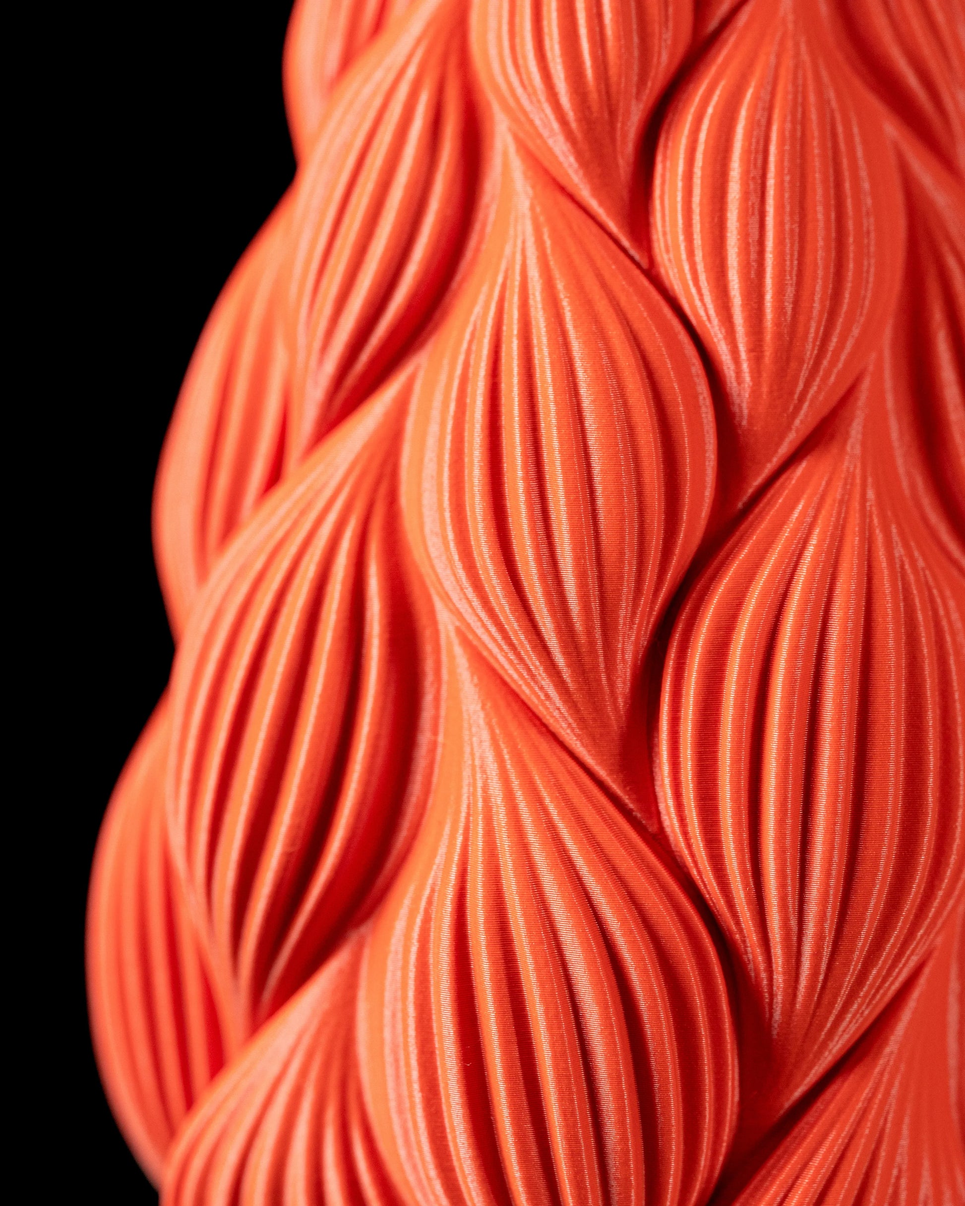 Vase rouge orangé avec surface ondulée en relief rappelant des formes de gouttes allongées, finition mate, silhouette.