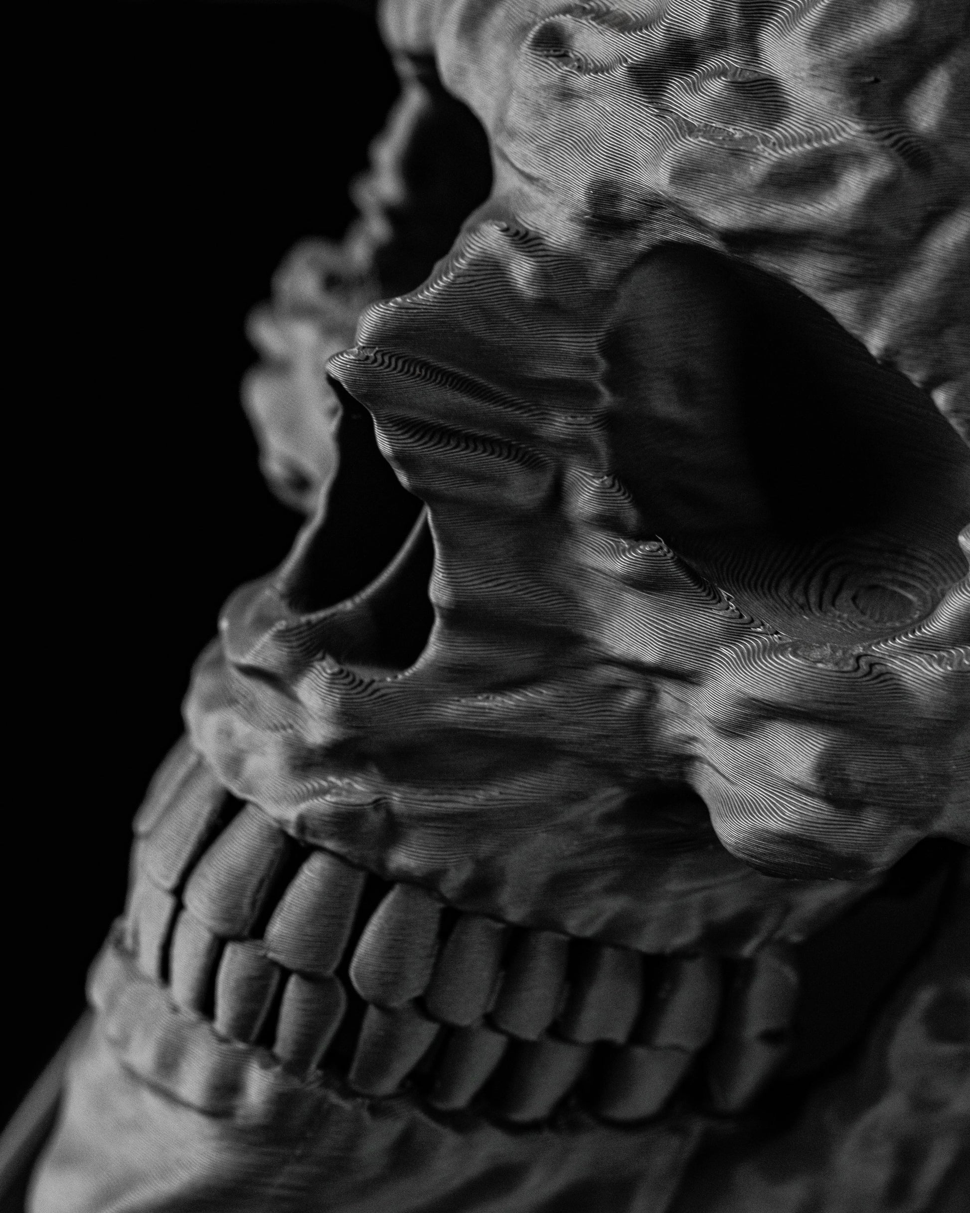 Pot décoratif en forme de crâne humain gris foncé avec détails réalistes et texture granuleuse, style moderne et sculptural.