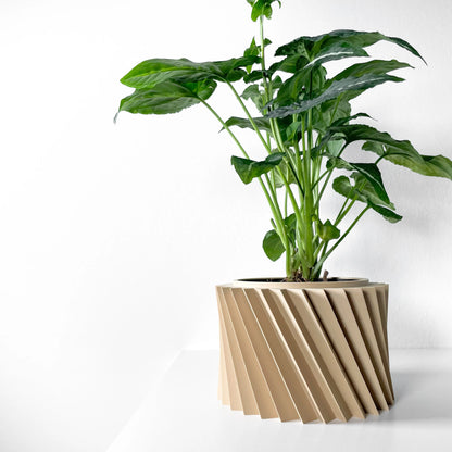 Pot décoratif beige en matériau moderne avec surface sculptée en spirale, plante verte aux grandes feuilles épaisses placée.