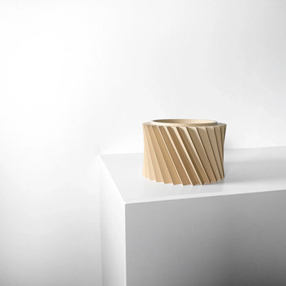 Pot décoratif couleur sable avec surface texturée en spirale moderne, forme cylindrique, posé sur un coin blanc minimaliste.