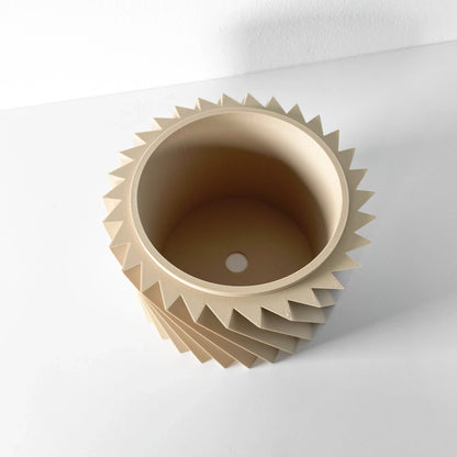 Pot décoratif beige en matériau mat avec design géométrique en spirale formant des pointes autour du bord supérieur,.